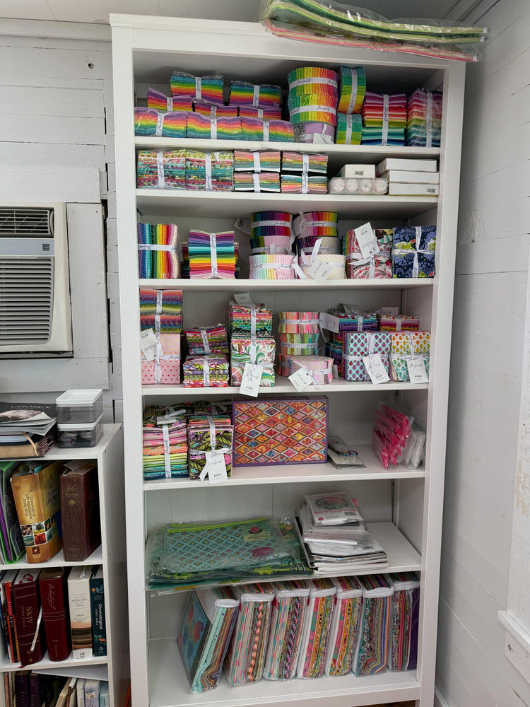 Pre-cut quilt fabric bundles including fat quarters, jelly rolls, and charm packs